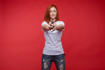 Waist up of smiling attractive woman holding glue gun and aiming isolated on red background