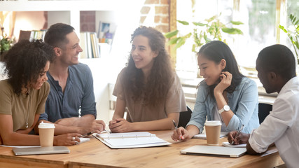 Smiling diverse people brainstorm discussing project at meeting