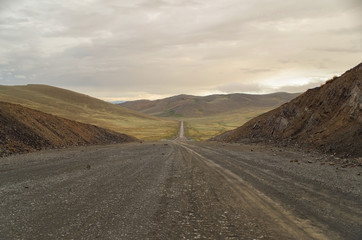 Mongolian Altai. Dirt road and mountain valley at evening. Road from Russia, near Ulaanbaishint Check Point. Nature and travel. Mongolia, Bayan-Olgii Province