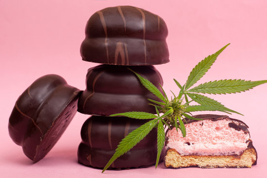 medical chocolate sweets with THC. chocolate marshmallows and cannabis bud on a pink background
