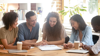 Smiling multiracial people discuss paperwork at meeting