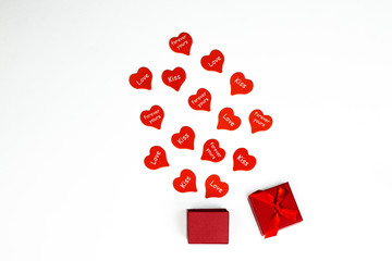 Open red gift box with heart shaped party confetti on white background. Valentine’s day, holidays and romantic. Flat lay background.