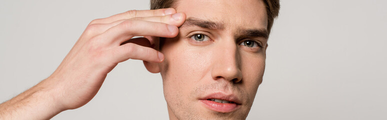 Obraz premium sexy man with muscular torso touching face isolated on grey, panoramic shot