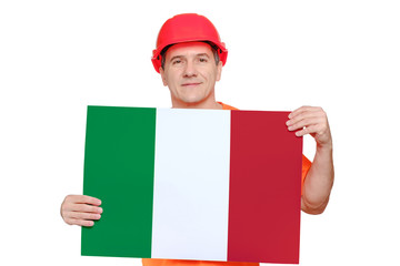 Portrait smiling middle-aged handsome worker wearing red hard hat, holding paper with italian flag in hands.