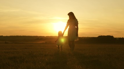 concept of a happy childhood. child mom play in the meadow in the sun. mother and little daughter...