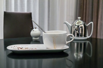 dirty cup after tea with smudges and leftover dessert on a plate stand on the kitchen table