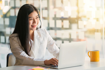 Young female customer support phone operator with headset working in call center.	