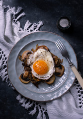 Fried egg on a plate with fried mushrooms for breakfast