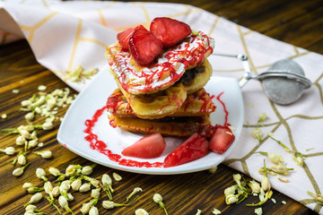 Stack of heart wafers with fresh strawberries on an old wooden surface