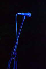 Microphone on the stage with blue illumination on the black background