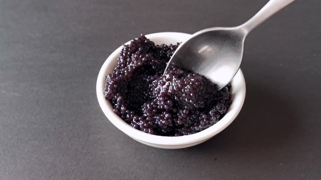 The process of laying black caviar in a white plate.  