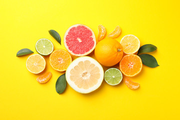 Citrus fruits and leaves on yellow background, top view