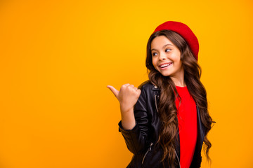 Close-up portrait of her she nice attractive charming glad cheerful long-haired girl pointing thumb back recommend solution copy space isolated over bright vivid shine vibrant yellow color background