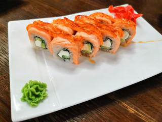 Set of baked Philadelphia sushi rolls on a white rectangular plate.