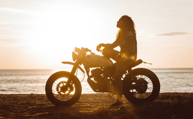Schönes Mädchen, das Spaß daran hat, ihr benutzerdefiniertes Cafe Racer-Motorrad zu fahren