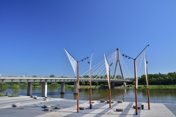 Wiszący most nad rzeką na bezchmurnym niebie w gorący, letni dzień. © W Korczewski