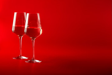 Two full glasses of wine over red background