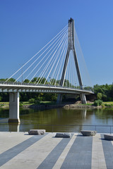 Wiszący most nad rzeką na bezchmurnym niebie w gorący, letni dzień.