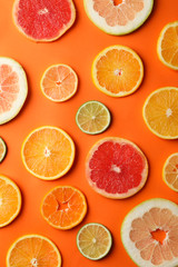 Many citrus fruits slices on orange background, top view