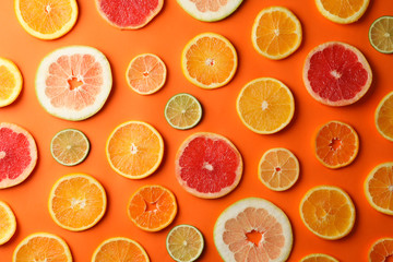 Many citrus fruits slices on orange background, top view