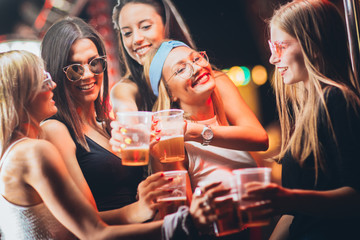 Female friends toasting with beer at the music festival