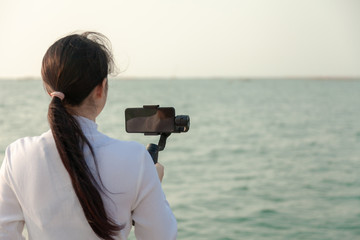 Obraz premium Blogger Asian woman record vlog video and sharing content on streaming platform with Social Network. female enjoy in front of camera using mobile phone make vlogging live feeds on social media network