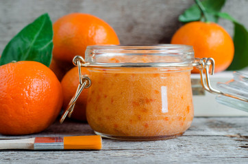Homemade tangerine facial mask (exfoliating sugar scrub) in the glass jar. Mandarin orange DIY cosmetics and spa recipe. Top view, Copy space.