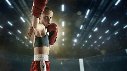 Stronger then ever. Young female kickboxing fighter training in the gym. Caucasian blonde girl in...