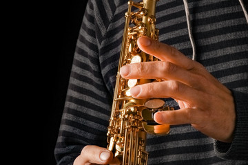 soprano saxophone in the hands of a guy on a black background