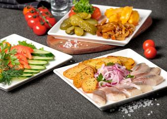 Assorted pickled vegetables pickled herring, chopped chives with potato, peppers, cucumbers, tomatoes, capers, salt and herbs. Set of vegetables snacks for alcohol vodka. Russian traditional cuisine.