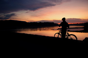 Fototapeta premium silhouette of bicycle rider at sunset, healthy lifestyle and sport concept background