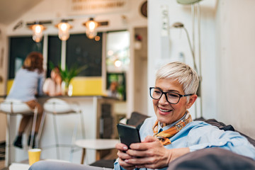 Home portrait of a positive senior woman with smart phone, copy space.