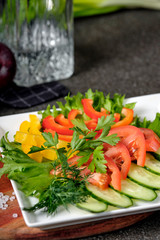 Assorted fresh vegetables - cucumber, tomato, pepper and herbs in white bowl plate. Set of vegetables snacks for alcohol vodka. Close up, selective focus.