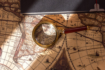 old vintage world map magnifying glass and book, travel and tourism concept