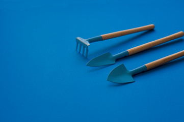 resource of gardening tools shovels and rake on blue classic background