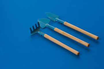 resource of gardening tools shovels and rake on blue classic background. top view