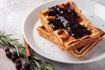 Belgian waffles with ice cream on a white plate and rosemary berry jam. Waffer with jam and icecream on craft background.