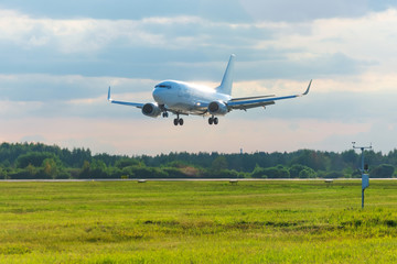 Fototapeta na wymiar Passenger plane lands on runway at airport, early evening.