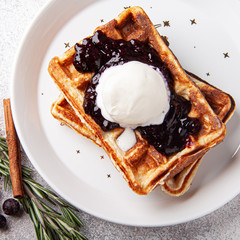 Belgian waffles with ice cream on a white plate and rosemary berry jam. Waffer with jam and icecream on craft background.