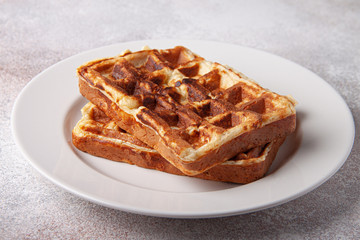 Belgian waffles on a white plate and craft background. Tasty waffer close up.