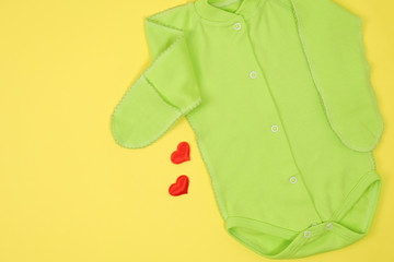 Bodysuit for newborn baby on yellow background. Expecting a baby concept. 