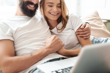 Fototapeta premium Cropped image of caucasian laughing couple using laptop and hugging