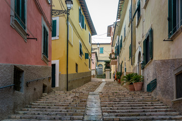 Fototapeta na wymiar Uphill walking street of Portoferraio with traditional colorful houses, Elba island, Italy