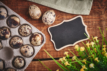 Quail eggs on wooden table close-up. Festive decoration with flowers for Easter with empty copy space for your text.