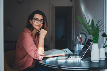 Pretty young woman an advertising copywriter in eyeglasses working at home using laptop, female...
