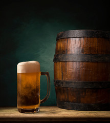Beer barrel with beer glasses on a wooden table. The dark brown background.
