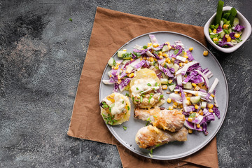 Top view Appetizing baked chicken legs with potatoes, cheese and red salad. Copy space