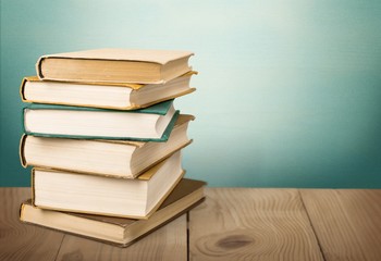 Stack books with wooden desk on pastel background
