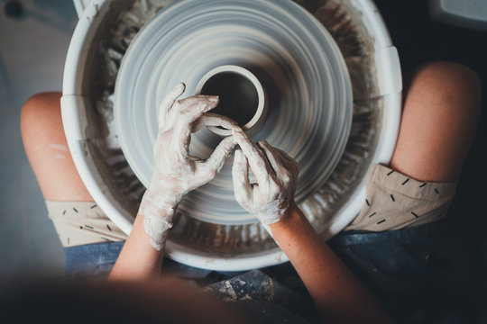 Top view of female potter's hands working on pottery wheels with eco friendly clay makes mug, concept for workshop and master class, Handcraft Ceramic Art People - Powered by Adobe