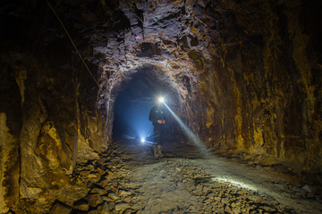 Underground gold mine shaft tunnel drift with miner and light